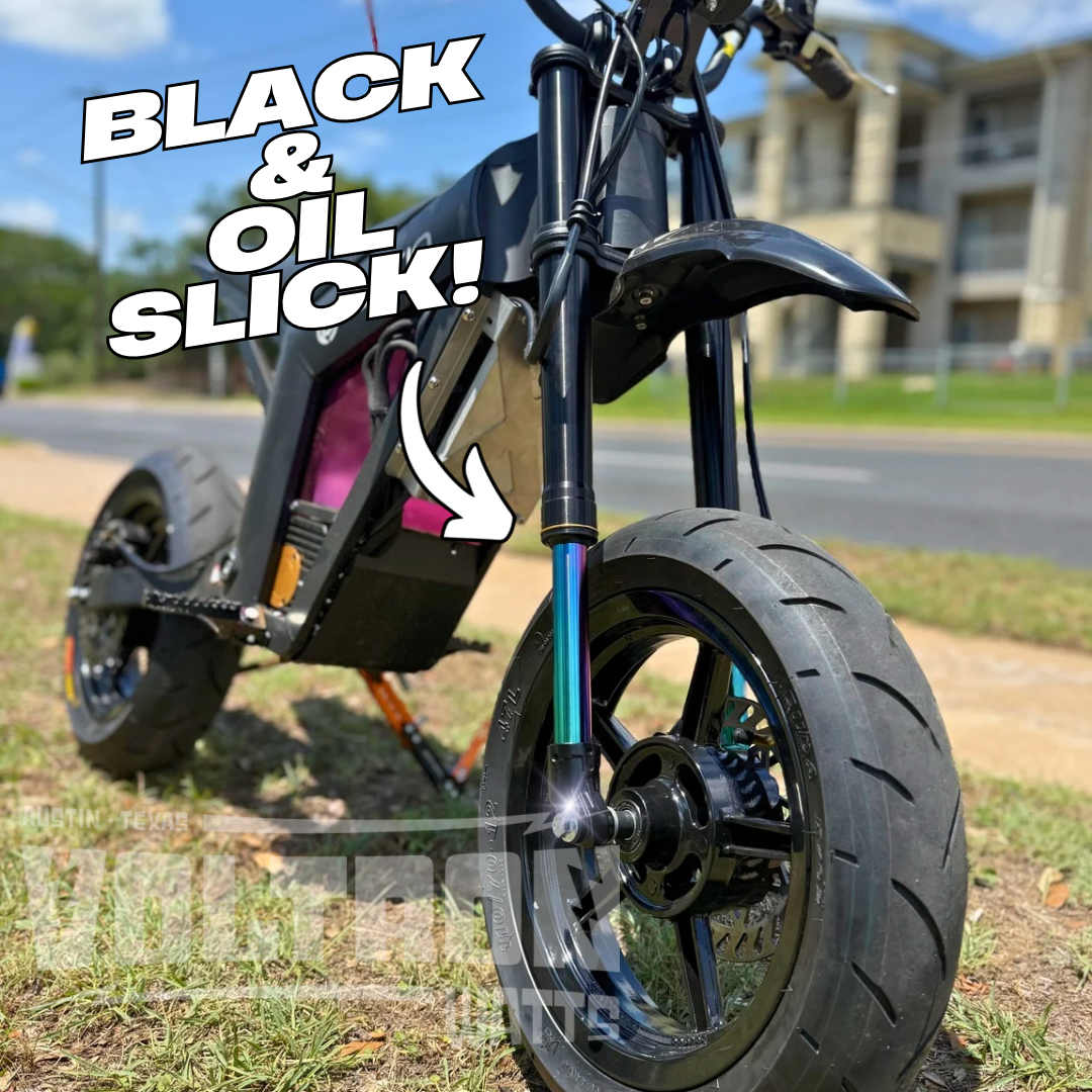 Close-up of a motorcycle wheel with text 'Black & Oil Slick!' on a grassy area.