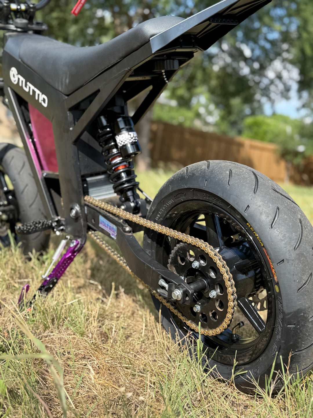 Close-up of a black electric bike with 'Tutto' branding on a grassy area.