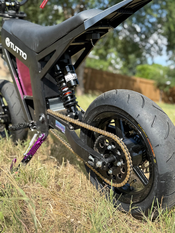 Close-up of a black electric bike with 'Tutto' branding on a grassy area.