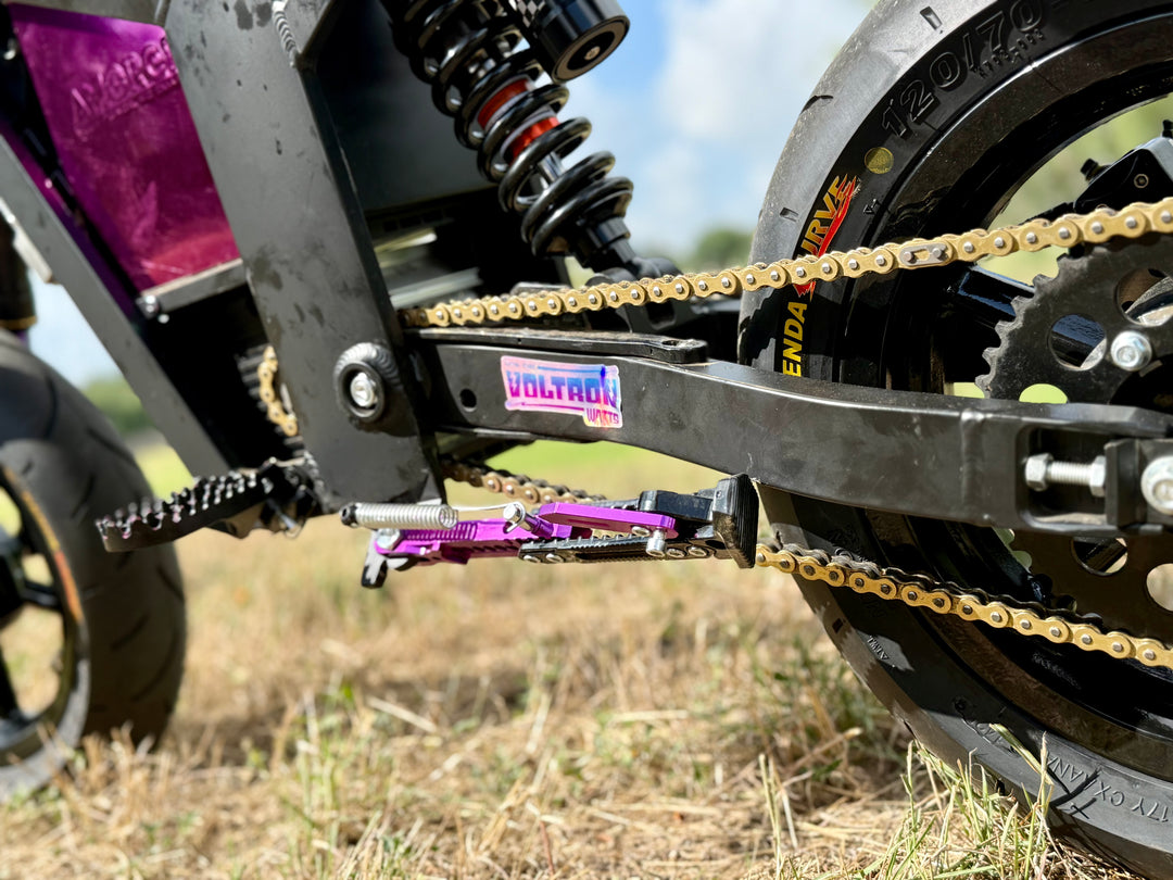 Close-up of a Tuttio Soleil 01 motorcycle kickstand chain and sprocket with a blurred natural background