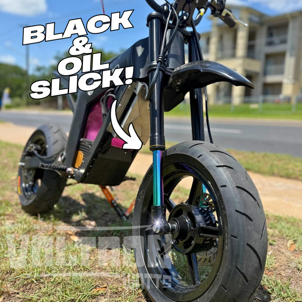Close-up of a motorcycle wheel with text 'Black & Oil Slick!' on a grassy area.