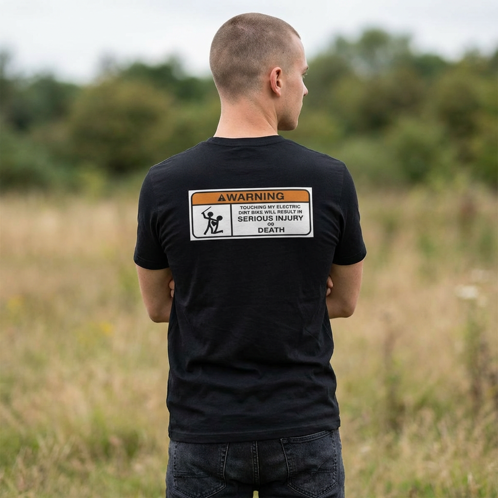 Person wearing a black t-shirt with a warning label in an outdoor setting