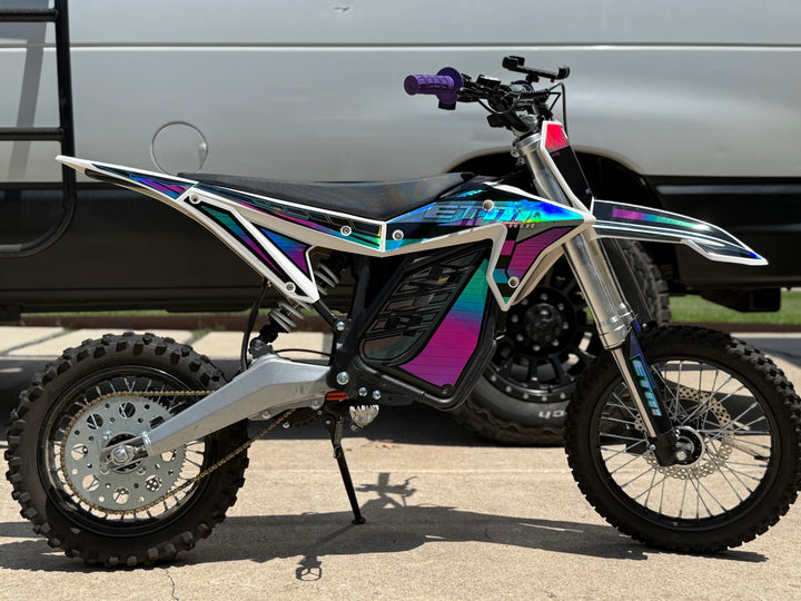 Motorcycle with a colorful design parked next to a van.