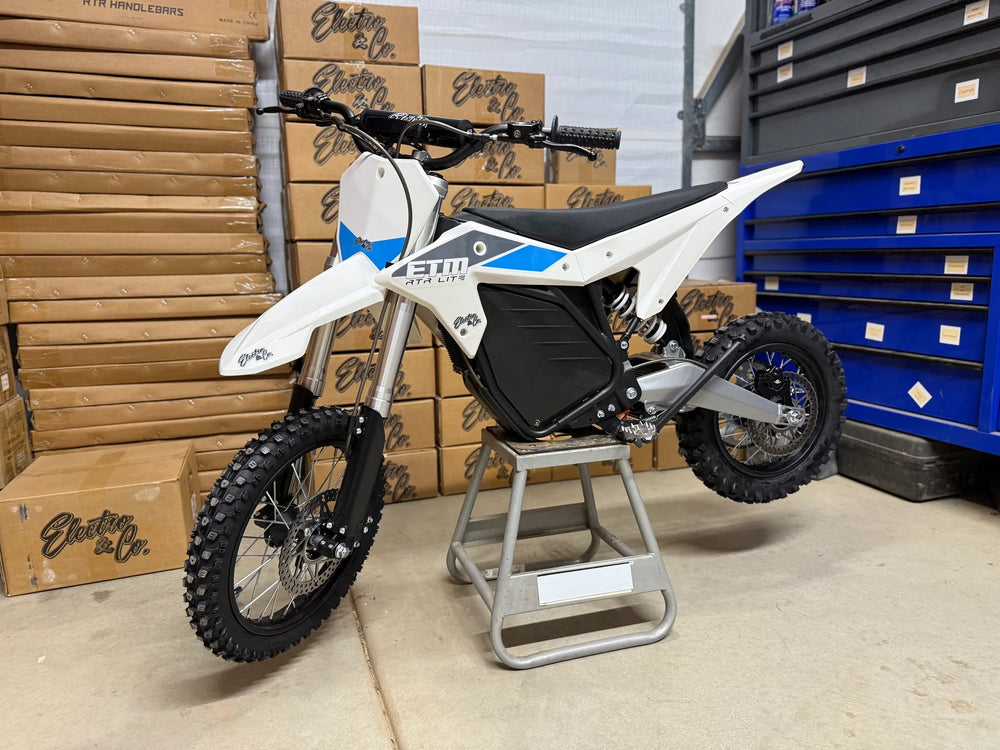 Electric dirt bike on a stand with boxes and a toolbox in the background