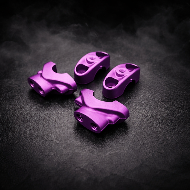 Four purple metal components on a dark textured surface