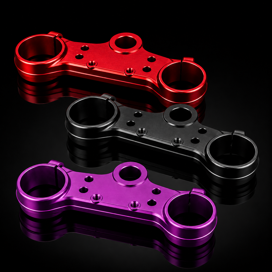 Three metal linkage components in red, black, and purple on a reflective black surface.