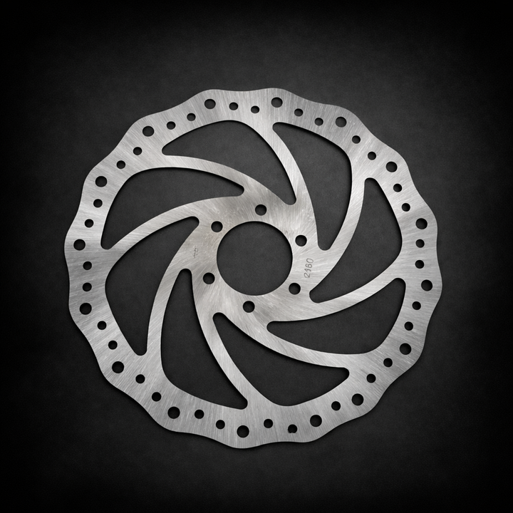 Metallic disc brake rotor on a dark background