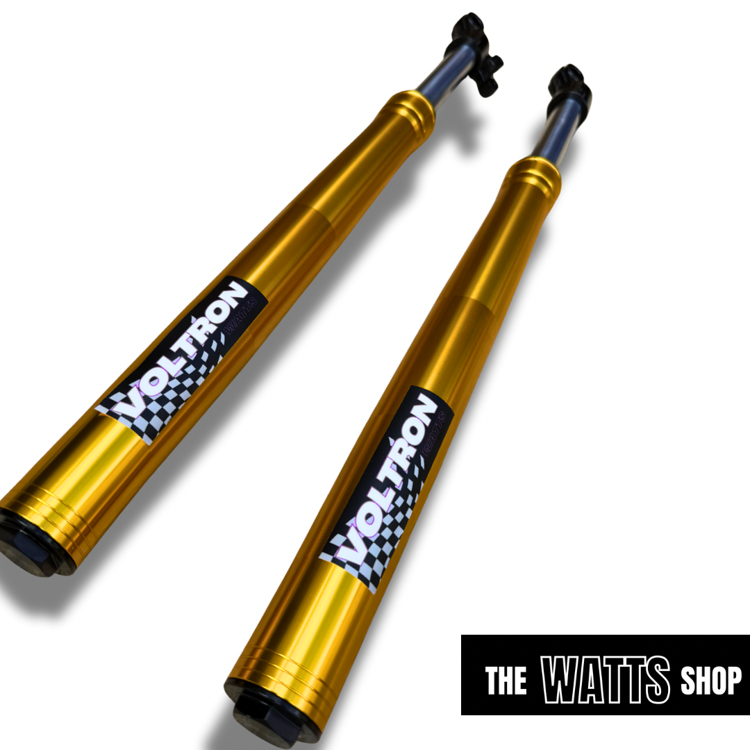 Two gold shock absorbers with Voltron branding For Tuttio Soleil on a white background, featuring 'The Watts Shop' logo.