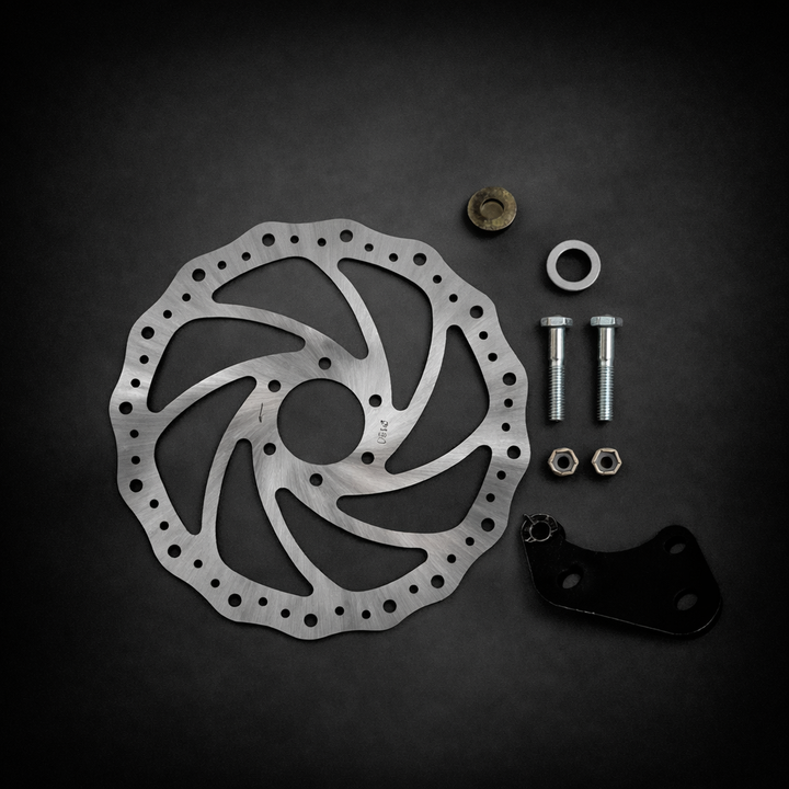 Metallic disc brake rotor with hardware on a dark background