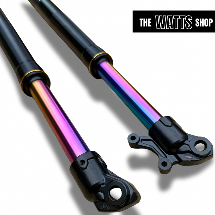 Two Tuttio Soleil 01 shock absorbers with a rainbow-colored metal shaft on a white background, branded 'The Watts Shop'.