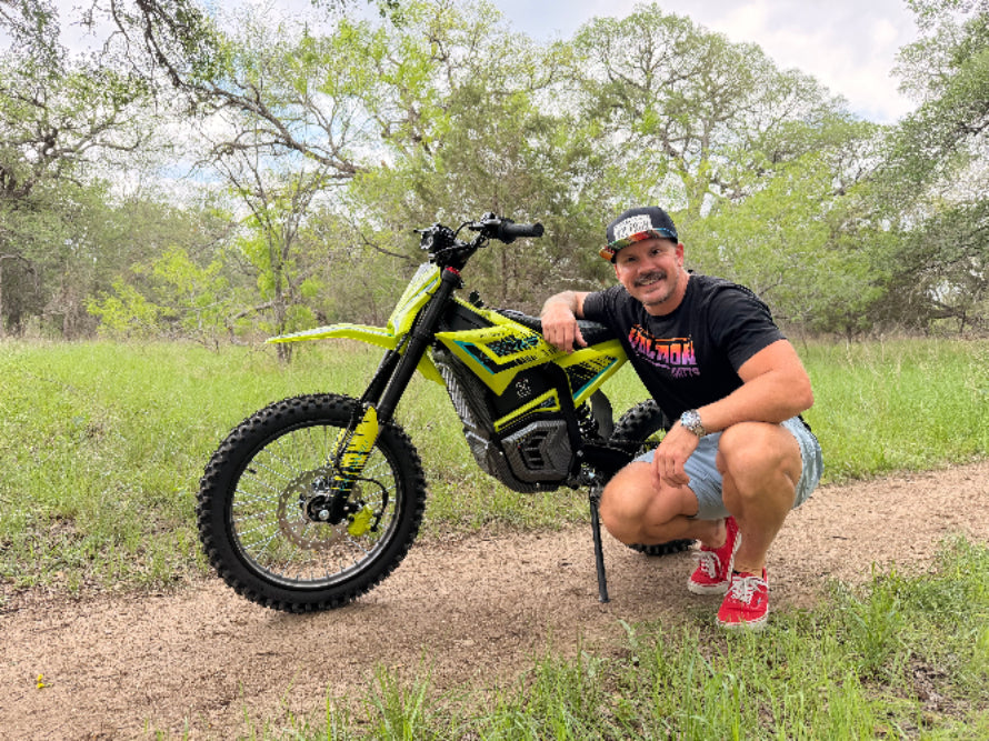 Man posing with a yellow electric bike in a natural setting