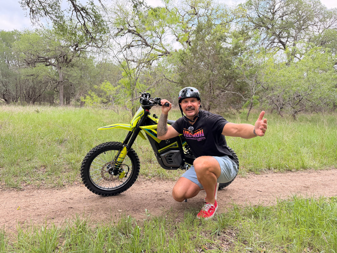 Man posing with a yellow electric bike in a natural setting