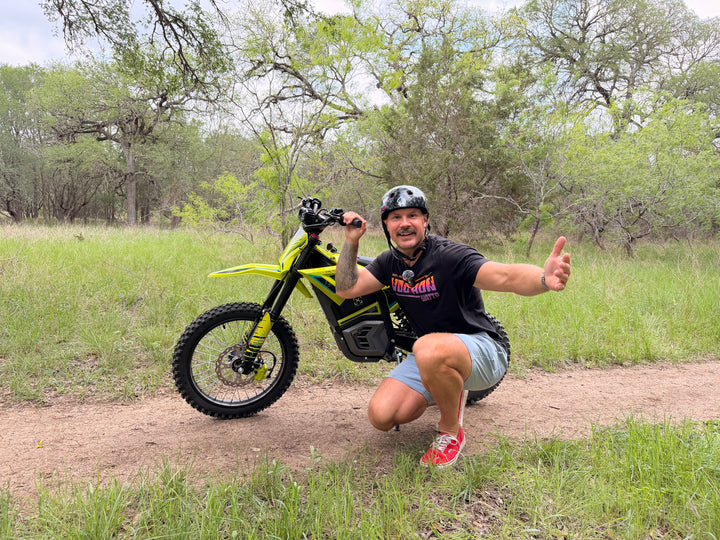 Man posing with a yellow electric bike in a natural setting