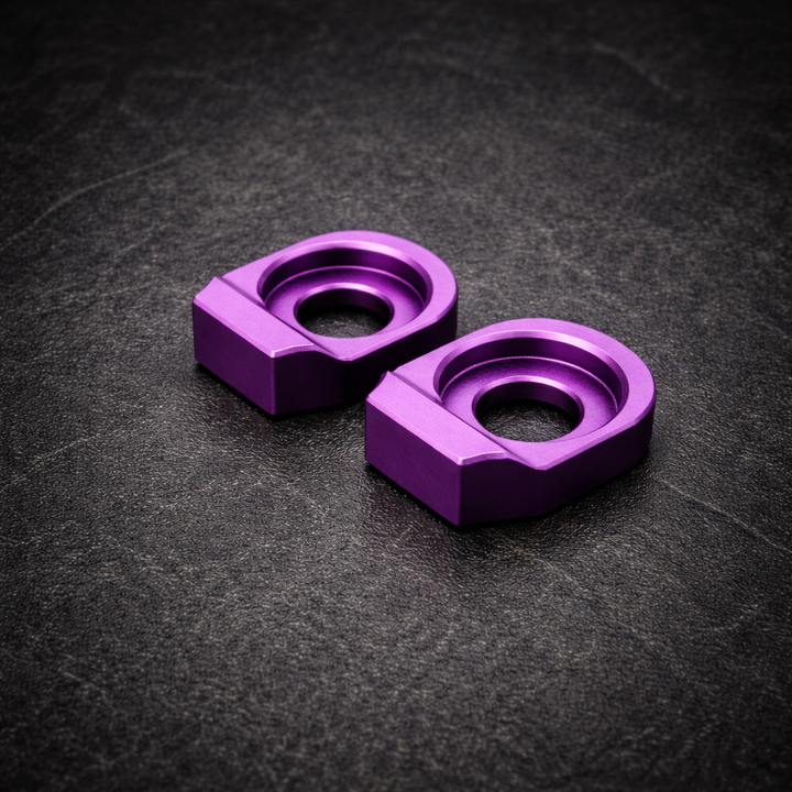 Two purple metal washers on a dark textured surface