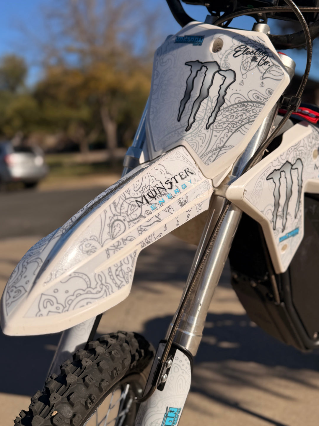 Close-up of a motorcycle with 'Monster Energy' branding on the handlebar guards.