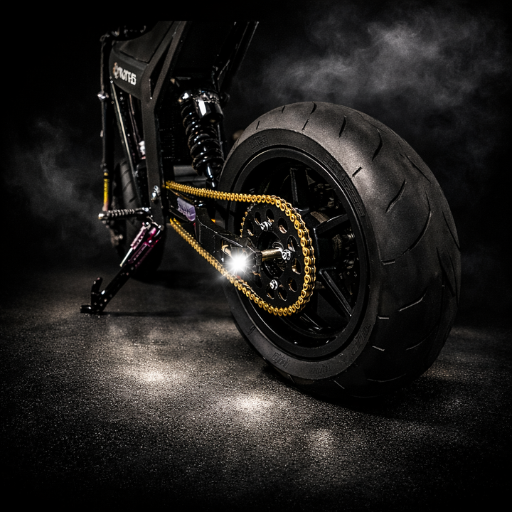 Close-up of a motorcycle wheel with chain on a dark background