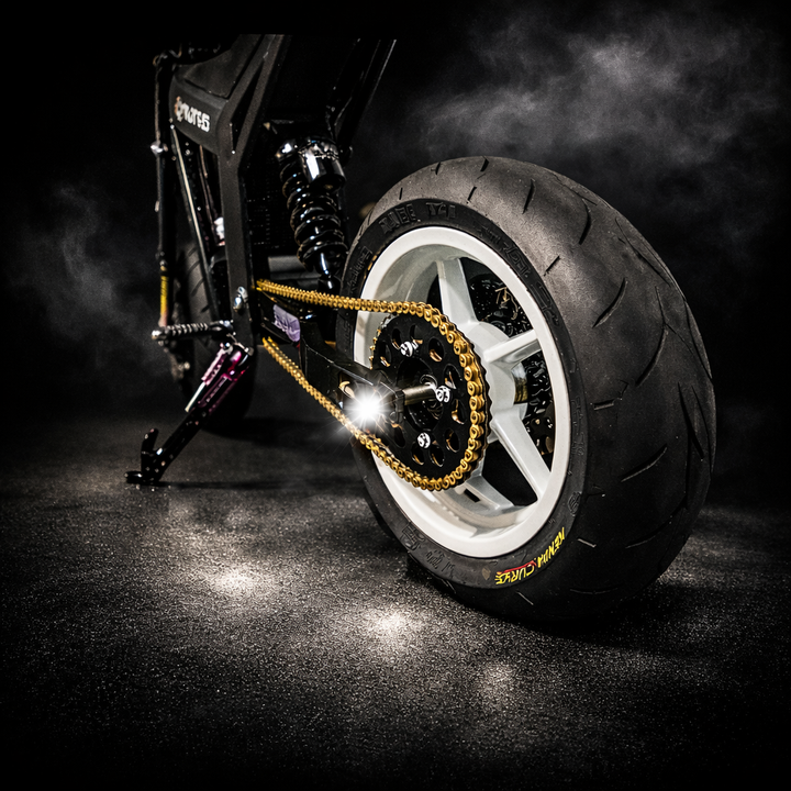 Close-up of a motorcycle wheel with chain on a dark background
