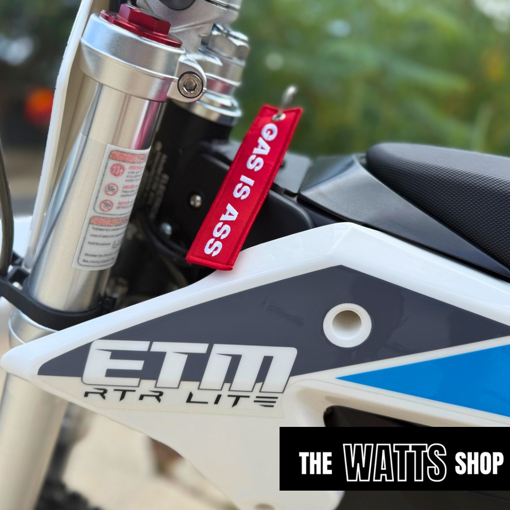 red key chain that says "gas is ass" on electric dirt bike by Voltron watts