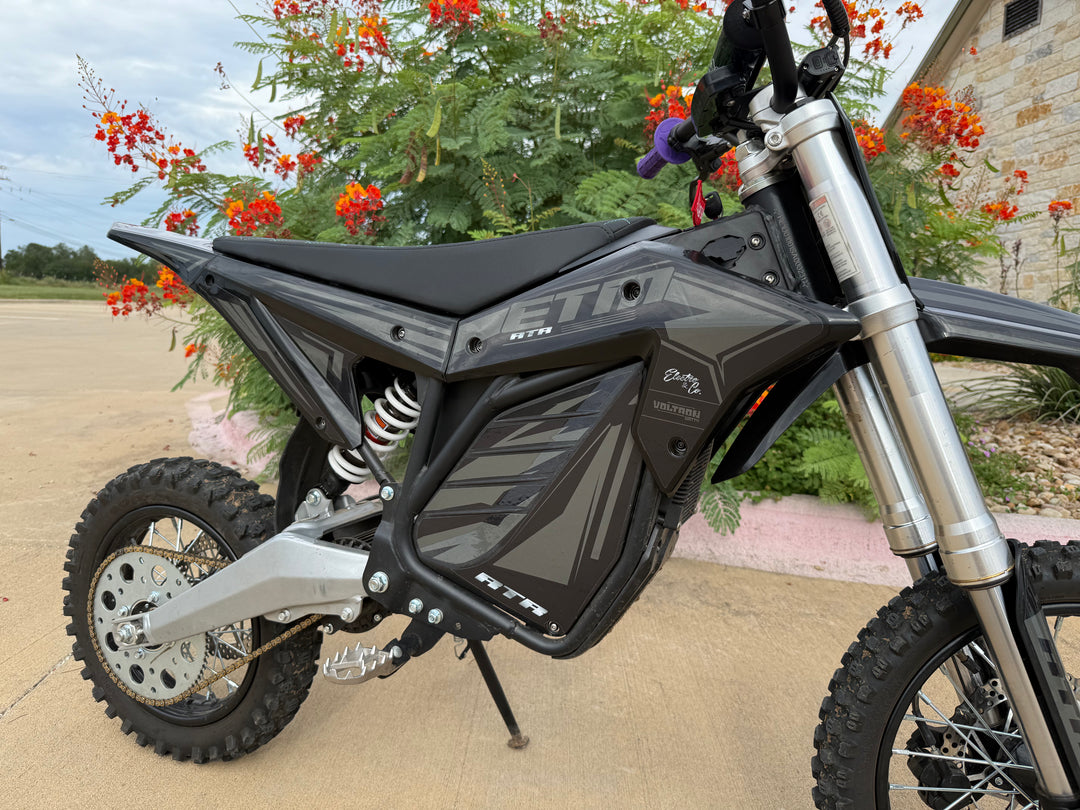 Black electric bike with 'Jetson' branding on a driveway with plants and flowers in the background